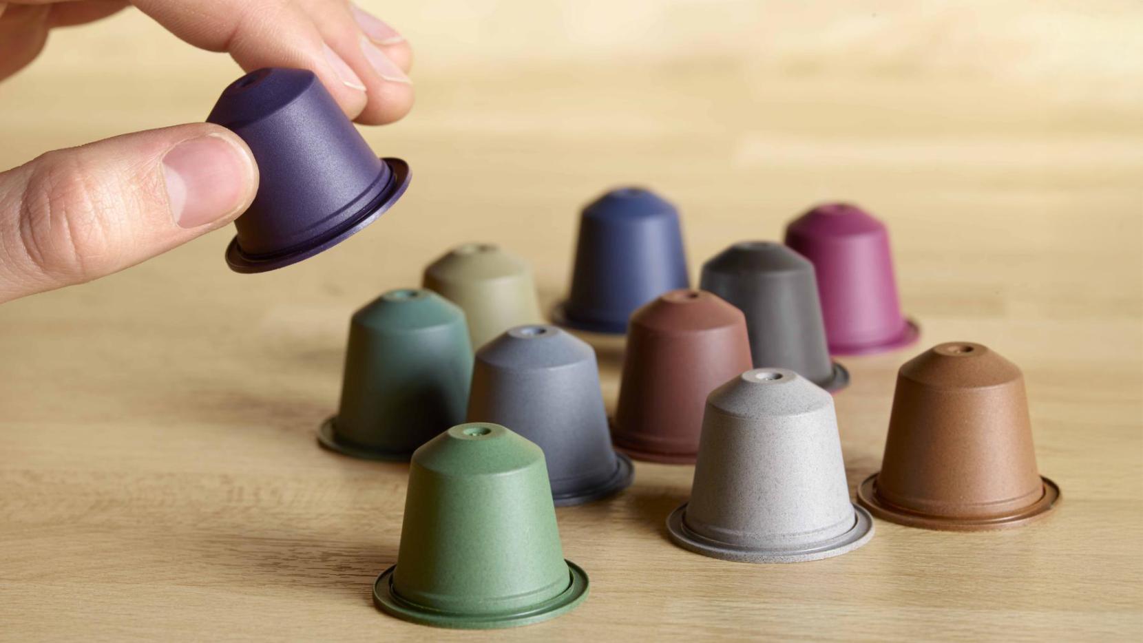 Blue Circle Coffee Capsules in hand with multiple colors on a wooden table