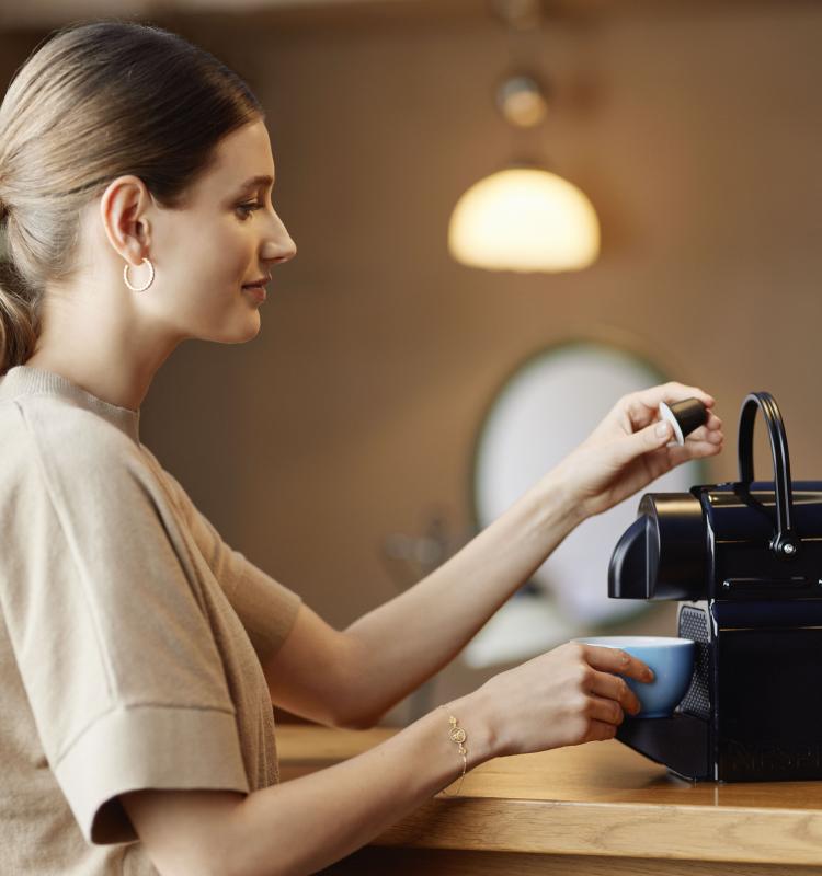 Woman taking a coffe with the Blue Circle Coffee Capsule at the Nespresso Machine