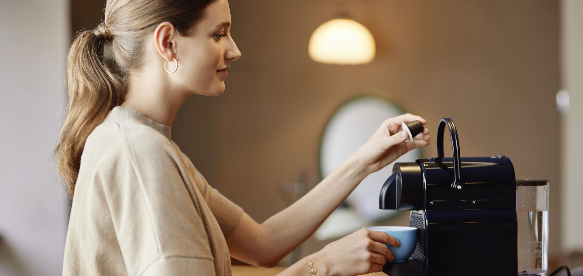 Woman taking a coffe with the Blue Circle Coffee Capsule at the Nespresso Machine