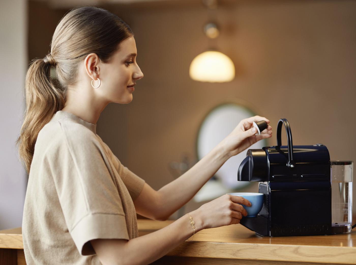 Woman taking a coffe with the Blue Circle Coffee Capsule at the Nespresso Machine